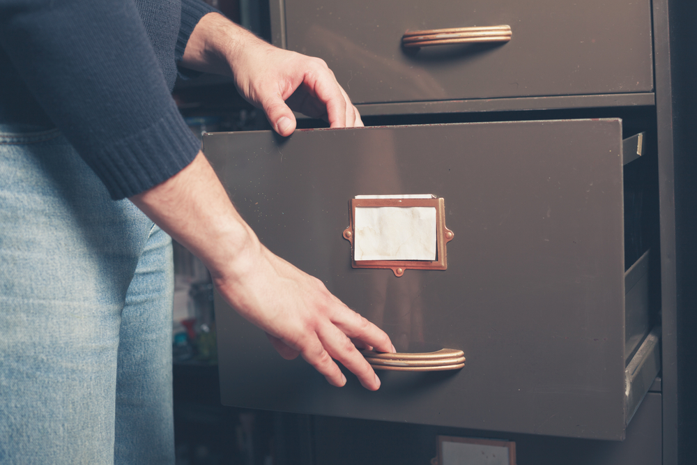 A young man is opening a file cabinet